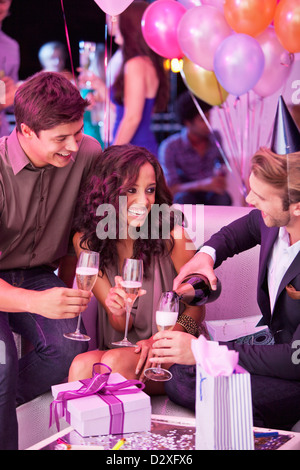 Lächelnden Freunde Champagner trinken und feiern Geburtstag im Nachtclub Stockfoto