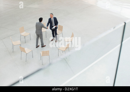 Kreis der Stühle um Geschäftsleute Händeschütteln Stockfoto