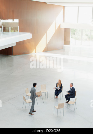 Geschäftsmann nähert sich Mitarbeiter im Kreis der Stühle Stockfoto