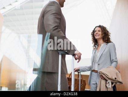 Lächelnde Geschäftsfrau im Gespräch mit Geschäftsmann in Flughafen Stockfoto