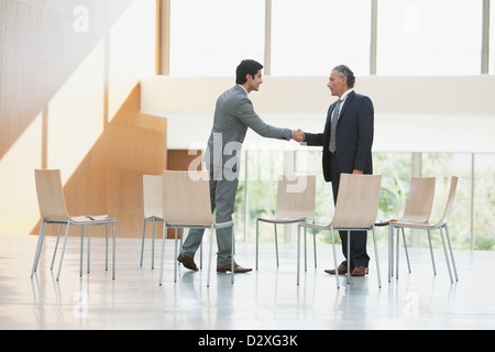 Stühle, die umgebenden Geschäftsleute Händeschütteln Stockfoto