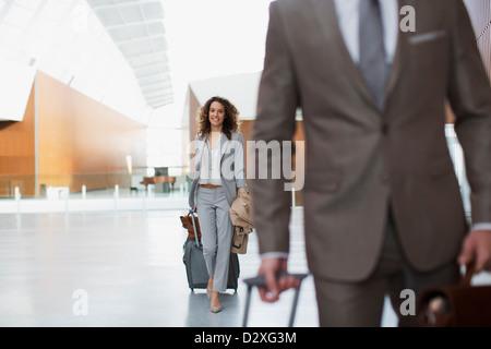 Lächelnde Geschäftsfrau ziehen Koffer im Flughafen Stockfoto