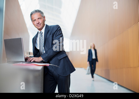 Porträt von zuversichtlich Geschäftsmann mit Laptop im Büro Stockfoto