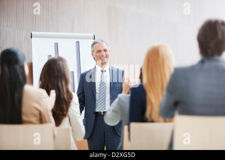 Business-Leute applaudieren Geschäftsmann am Flipchart stehen Stockfoto