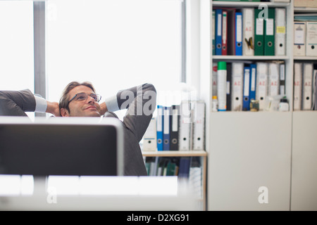 Glücklich Kaufmann mit Kopf in den Nacken und die Hände hinter den Kopf im Büro Stockfoto