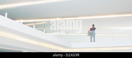 Geschäftsmann am Glas Balkongeländer im modernen Büro Stockfoto