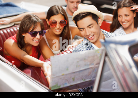 Freunde lesen Straßenkarte im Cabrio Stockfoto
