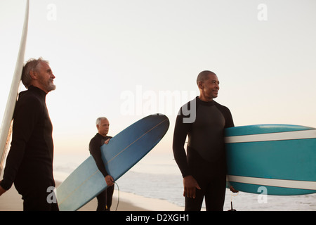 Ältere Surfer tragen Boards am Strand Stockfoto