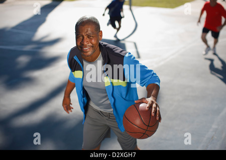 Älterer Mann spielen Basketball auf Platz Stockfoto