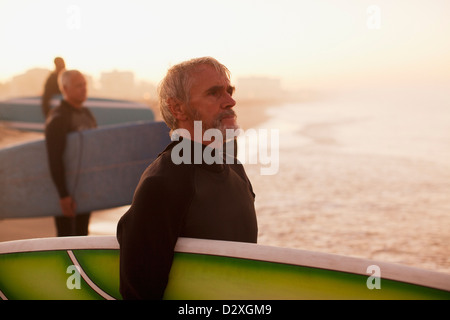 Ältere Surfer tragen Boards am Strand Stockfoto