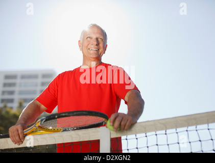 Älterer Mann mit dem Tennisspielen auf Platz Stockfoto