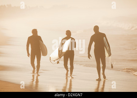 Ältere Surfer tragen Board am Strand