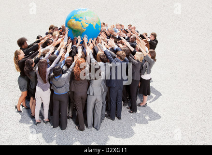 Menge von Geschäftsleuten im Huddle erreichen für globe Stockfoto