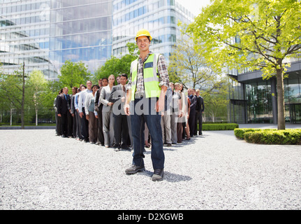 Porträt des Lächelns Bauarbeiter mit Geschäftsleuten im Hintergrund Stockfoto