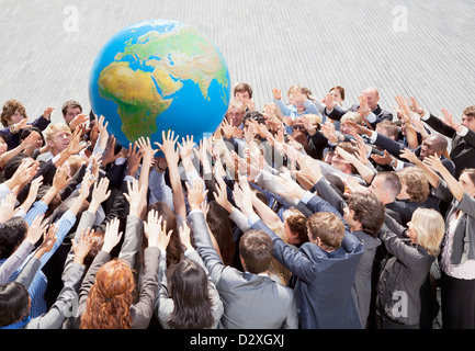 Masse der Geschäftsleute erreichen für globe Stockfoto