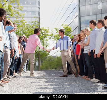 Geschäftsleute aus getrennten Teams Händeschütteln Stockfoto