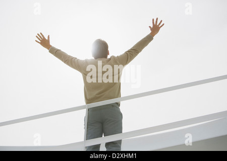 Sonne hinter Geschäftsmann mit erhobenen Armen Stockfoto