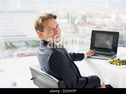 Porträt von lächelnden Geschäftsmann mit Laptop und Mittagessen Stockfoto