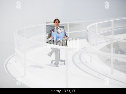 Geschäftsmann, sitzen im Stuhl mit Ordner auf erhöhten Laufsteg Stockfoto