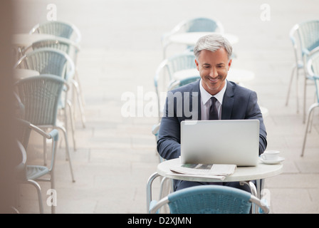 Lächelnde Geschäftsmann mit Laptop im Straßencafé Stockfoto