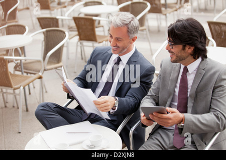 Lächelnde Geschäftsleute mit digital-Tablette und Unterlagen im café Stockfoto