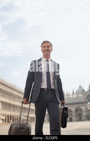 Lächelnd Geschäftsmann ziehen Koffer durch den Markusplatz in Venedig Stockfoto