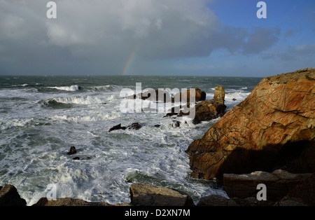 Starker Wellengang im Begriff Beg En Aud, mit einem Regenbogen auf dem Meer, wilde Küste von Quiberon-Halbinsel (Bretagne, Frankreich). Stockfoto