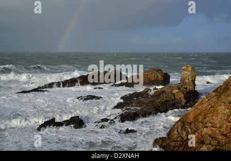 Starker Wellengang im Begriff Beg En Aud, mit einem Regenbogen auf dem Meer, wilde Küste von Quiberon-Halbinsel (Bretagne, Frankreich). Stockfoto