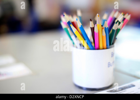 Topf mit Farbstiften auf Schreibtisch im Klassenzimmer der Grundschule Stockfoto