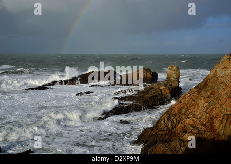 Starker Wellengang im Begriff Beg En Aud, mit einem Regenbogen auf dem Meer, wilde Küste von Quiberon-Halbinsel (Bretagne, Frankreich). Stockfoto