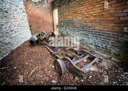 Ein völlig zerstörtes Auto in den Ruinen einer Garage in der zerstörten französischen Dorf Oradour-Sur-Glane. Rostige Chassis und Räder Stockfoto