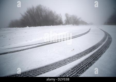 Reifenspuren sind im neu gefallene Schnee auf einer Straße auf Hoher Meissner in der Nähe von Hessische Lichtenau, Deutschland, 4. Februar 2013 abgebildet. Foto: UWE ZUCCHI Stockfoto