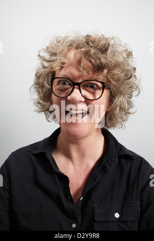 Frau mit lockigem Haar, die eine große Brille trägt, sieht leicht verrückt aus Stockfoto