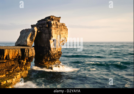 Wellen, die über Bildung Felsen bei Sonnenuntergang mit schönen Licht an Felswänden Stockfoto