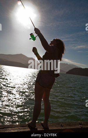 Eine junge Frau, die Fischerei vor einem Ponton an Akaroa, Canterbury, Südinsel, Neuseeland Stockfoto