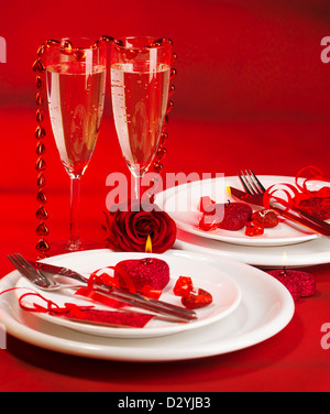 Bild der romantischen, weiße festlichen Teller serviert mit Silberbesteck und Weingläser und dekoriert mit herzförmigen Kerze Stockfoto