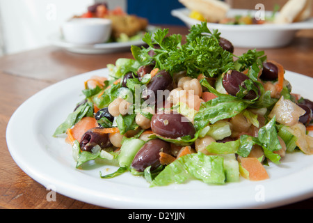 Teaneck Salat drinnen auf einem Holztisch mit anderen leckeren mediterranen Gerichten im Hintergrund. Stockfoto