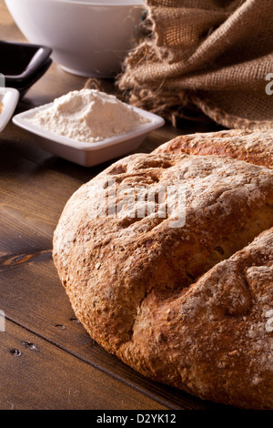 Rustikal frisch gebackenes Brot und Zutaten auf einem Holztisch Stockfoto