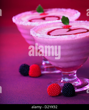 Bild von leckeren Milchshake auf lila Tisch, romantisches Dessert für Valentine Tag Urlaub, leckeres Eis mit frischen Himbeeren Stockfoto