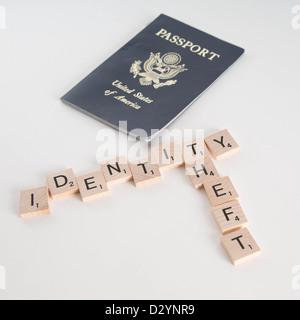 Identitätsdiebstahl geschrieben in Scrabble Buchstaben mit US-Pass im Hintergrund unscharf. Isoliert auf weißem Hintergrund. Stockfoto