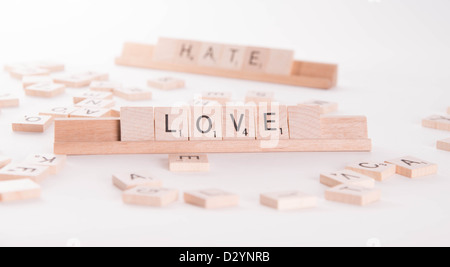 Hölzerne Scrabble Buchstaben buchstabieren "Love" und "Hassen". "Hasse" im Hintergrund unscharf. Isoliert auf weißem Hintergrund. Stockfoto