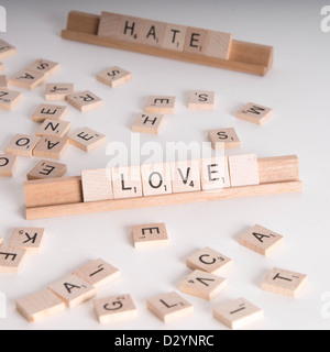 Hölzerne Scrabble Buchstaben buchstabieren "Love" und "Hassen". "Hasse" im Hintergrund unscharf. Isoliert auf weißem Hintergrund. Stockfoto