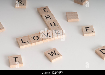 Wahre Liebe-Konzept. Hölzerne Scrabble Buchstaben Satz "Wahre Liebe". Isoliert auf weißem Hintergrund mit Licht Schatten Stockfoto