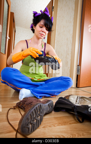 Hausfrau auf dem Boden sitzt und reinigt Schuhe Stockfoto