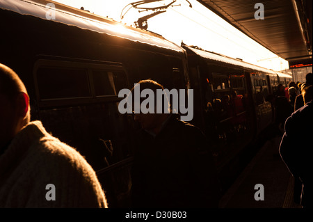 Silhouetten der Passagiere zu Fuß entlang einer belebten Bahnhof Bahnsteig in England. Stockfoto