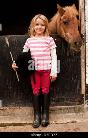 Junges Mädchen am Stalltür mit Pony in London, Großbritannien Stockfoto