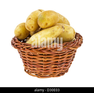 Einen alten Weidenkorb gefüllt mit gelben Gourmet-Kartoffeln auf einem weißen Hintergrund. Stockfoto