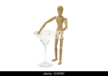 Eine weibliche Holzpuppe steht neben einem Cocktailglas Stockfoto