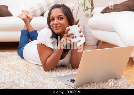 Junge glücklich indische liegend auf dem Boden Frau mit einem laptop Stockfoto