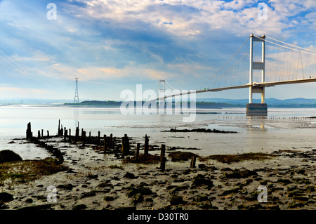 Fluß Severn mit ersten Severn Brücke Strommasten und Reste einer alten Anlegestelle in der Nähe von Aust bei Ebbe. Stockfoto